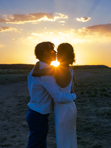 Couple silhouetted in a kiss as the sun sets over the desert