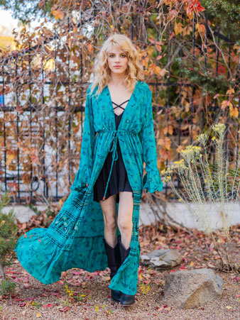 Model in a flowing teal kimono poses before autumn vines