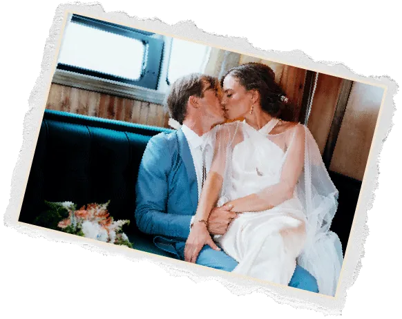Torn edge photo of a bride and groom kissing on a vintage trailer bench