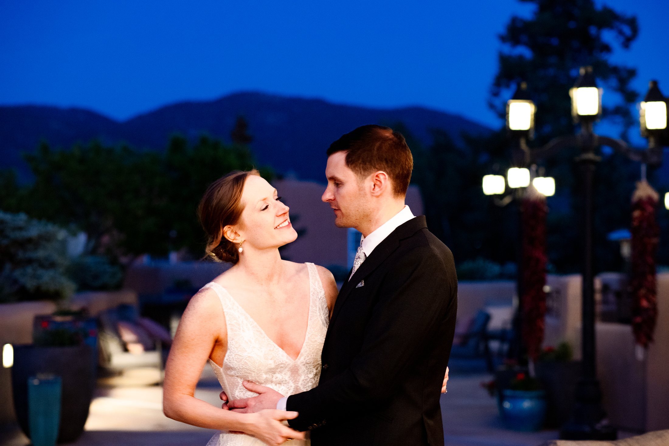 Bride and groom smiling at each other on a lantern lit terrace at blue hour