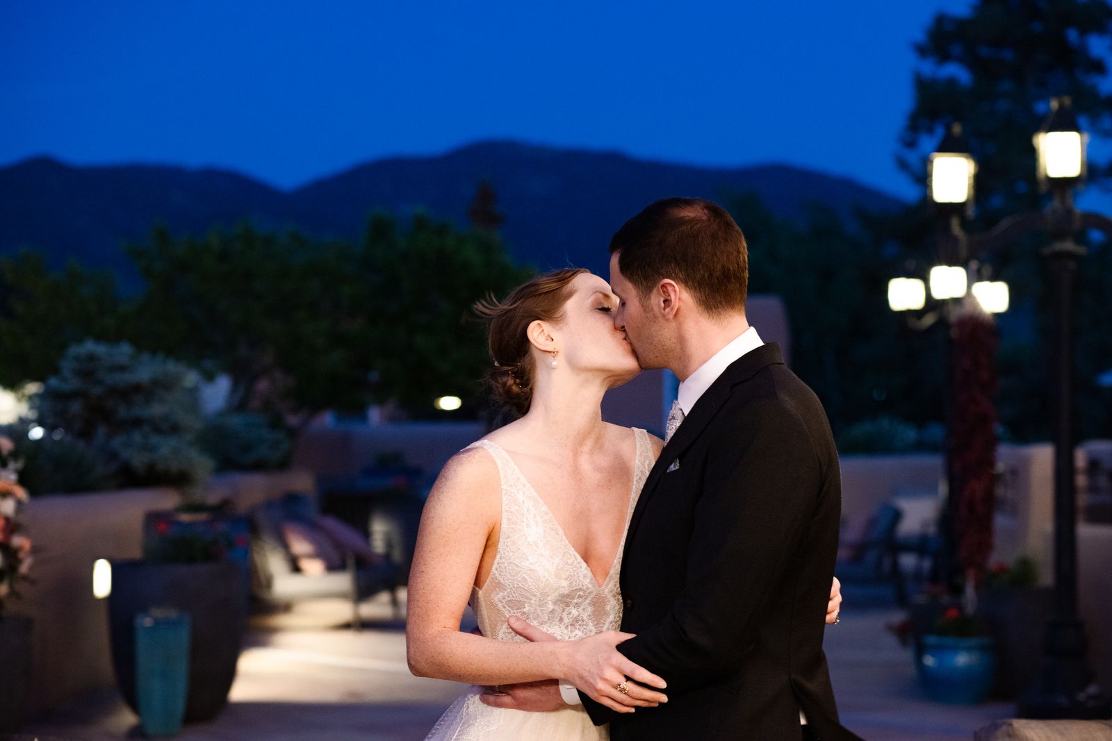 Couple kissing on a lantern lit terrace at dusk with mountains behind