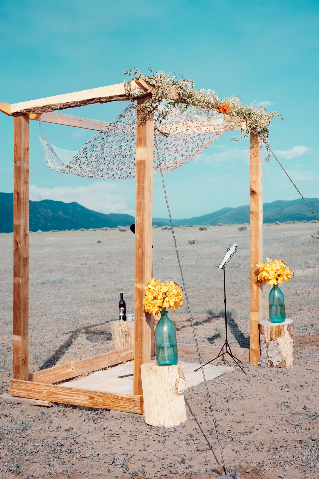 Wooden ceremony arch with flowers set in open high desert below mountains