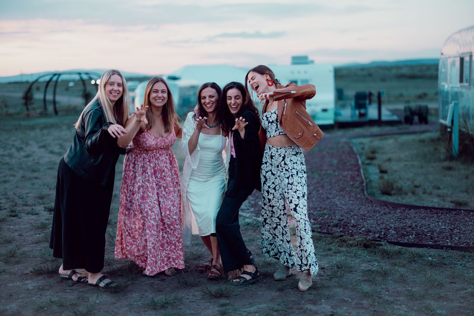 Group of women laughing together in a field beside vintage trailers