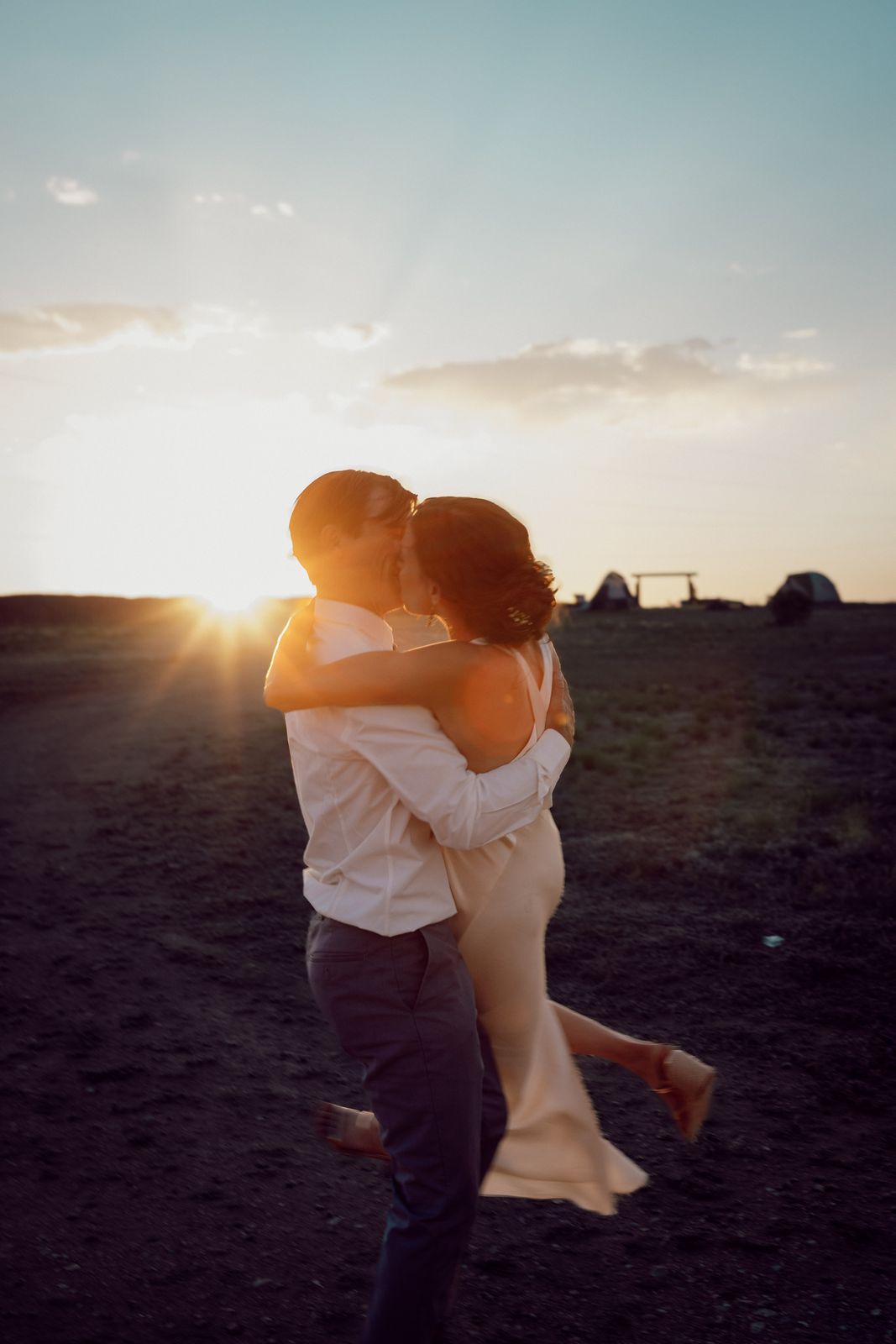 Groom lifting the bride in an embrace at sunset on the mesa
