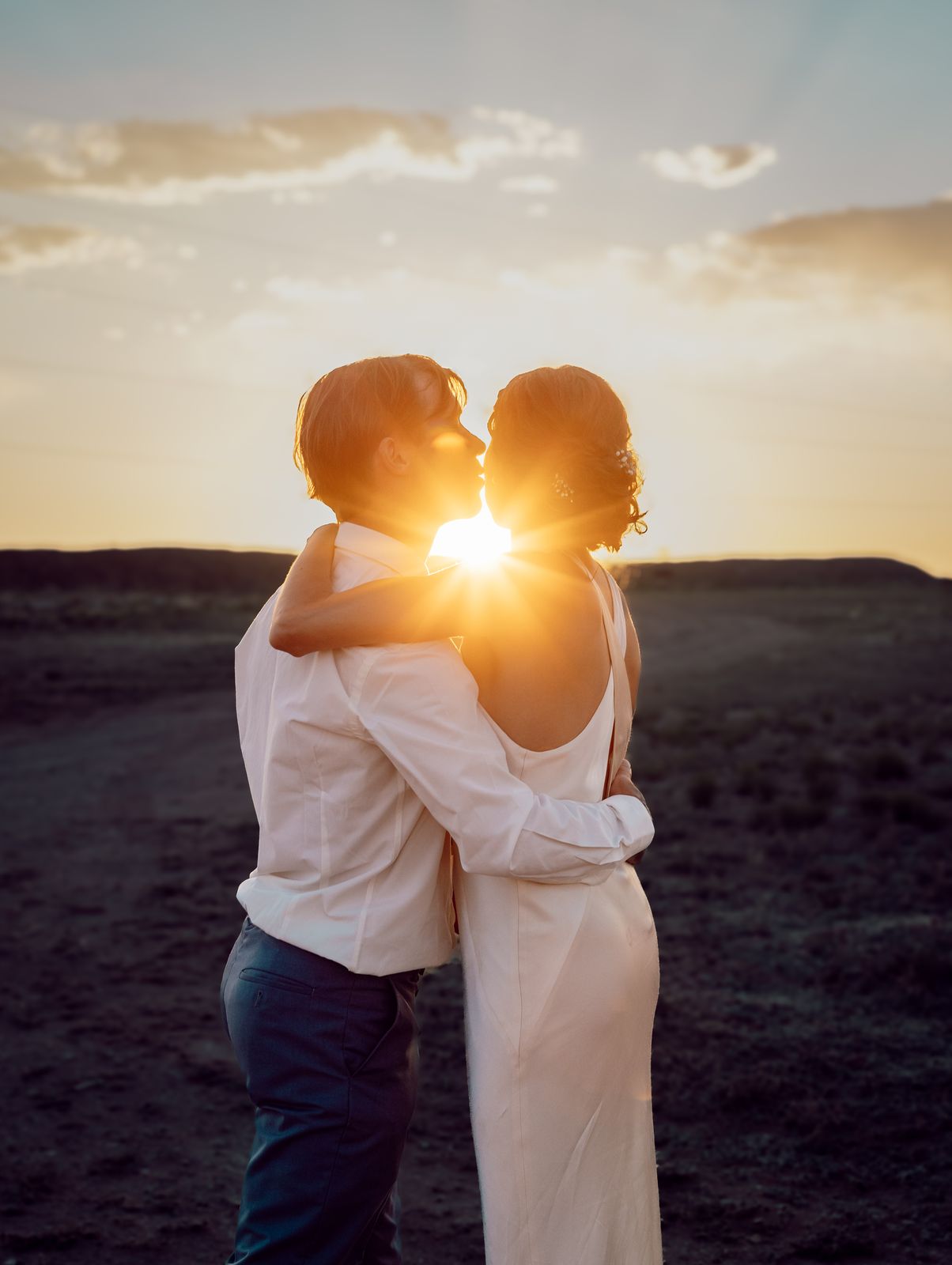 Couple kissing with the setting sun bursting between them