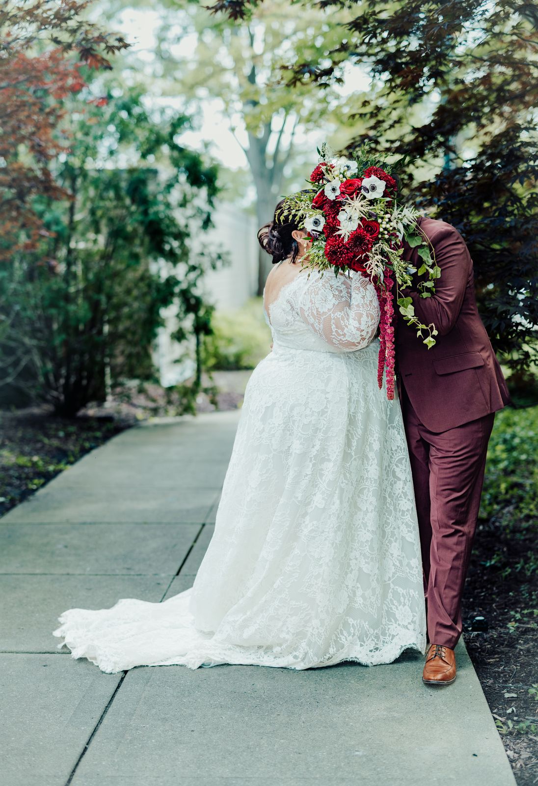 Couple kissing behind the bouquet on a garden path