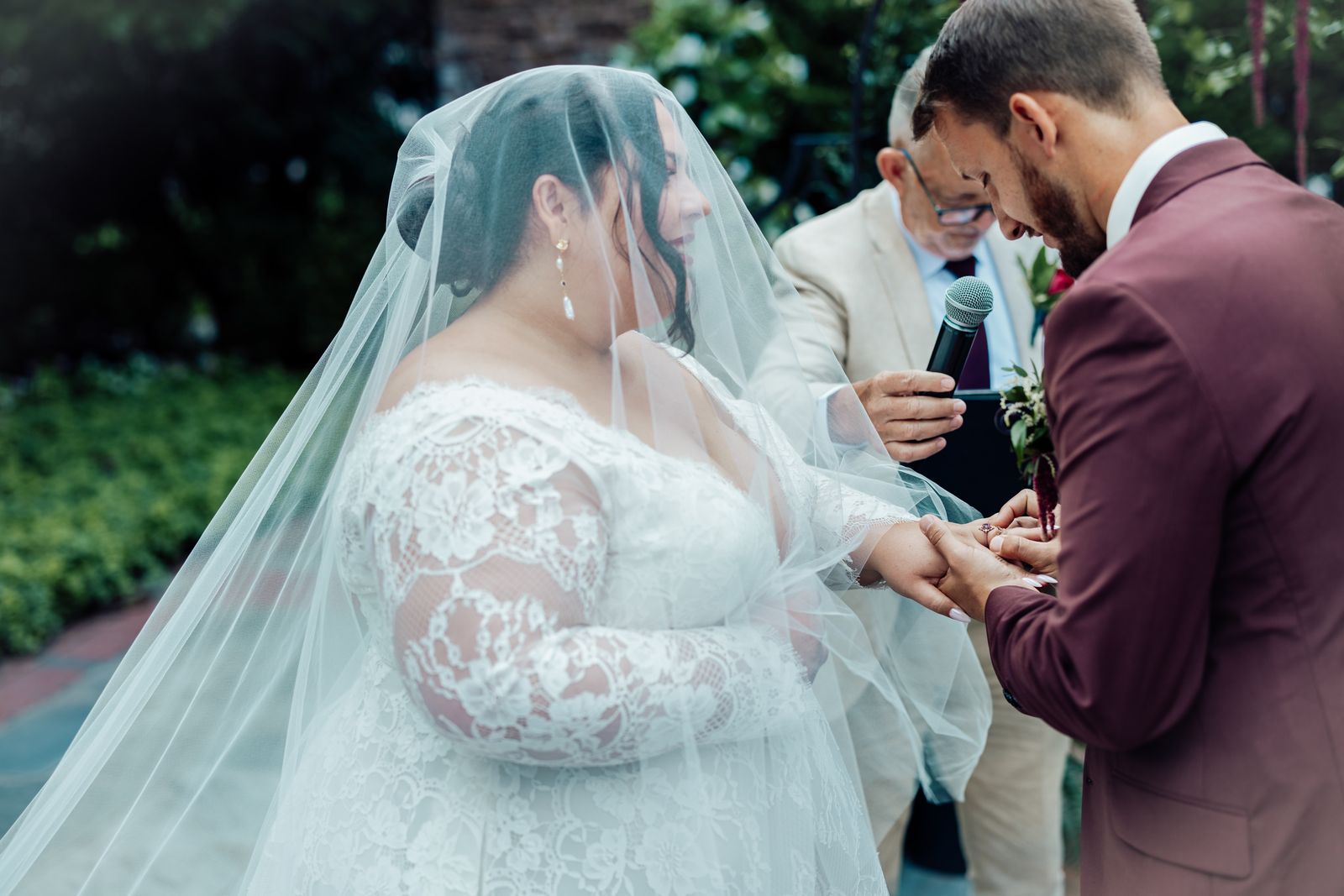 Bride and groom exchanging rings beneath her veil