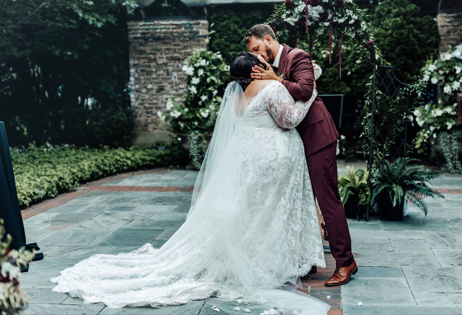 Couple kissing in a stone courtyard with the veil trailing on the ground