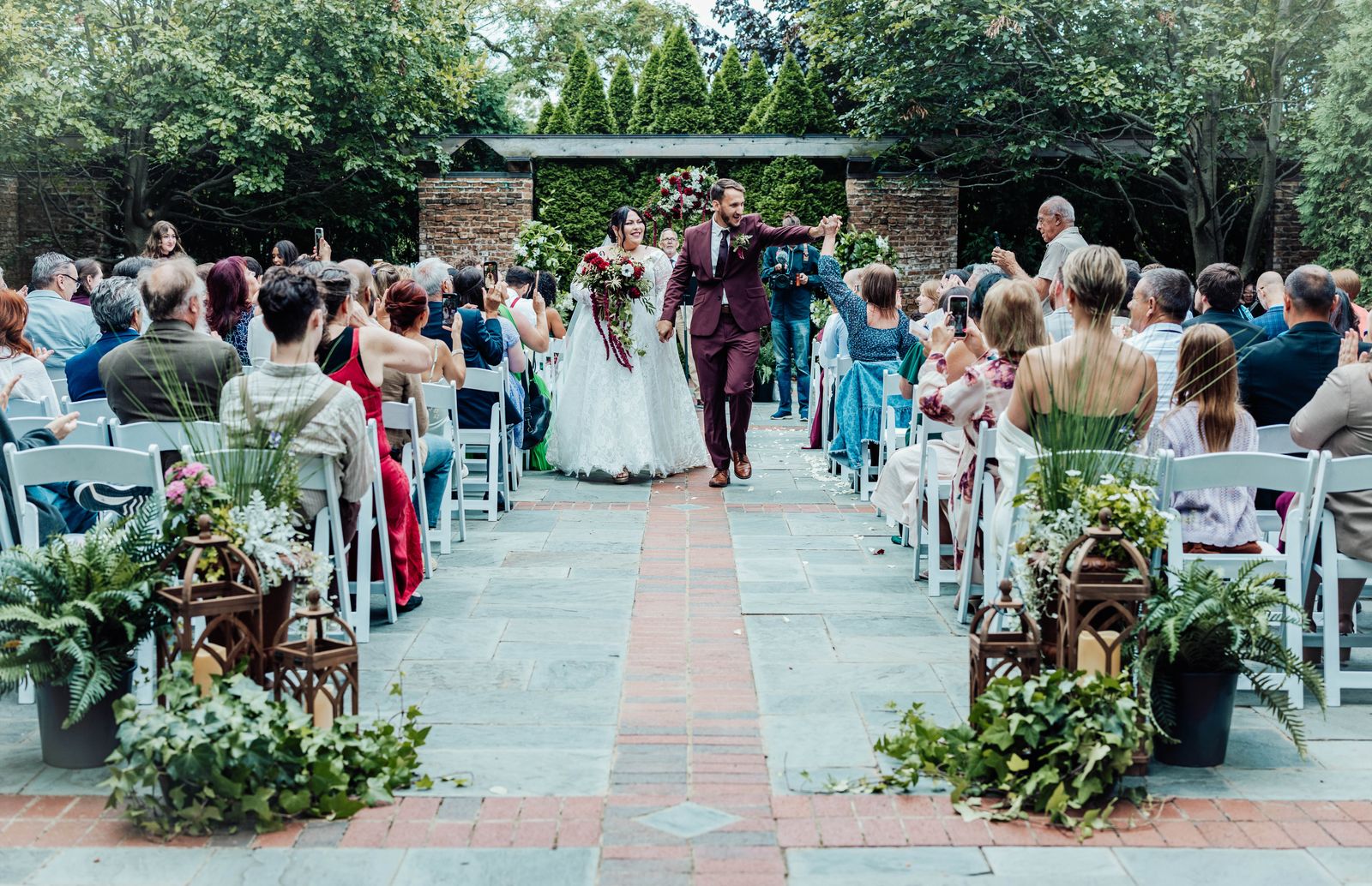 Newlyweds walking up the garden aisle as guests cheer