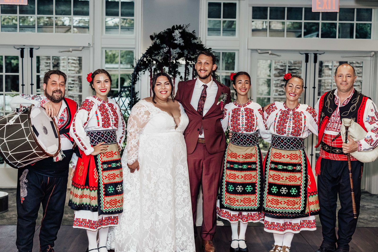 Couple posing with folk dancers in traditional embroidered costumes