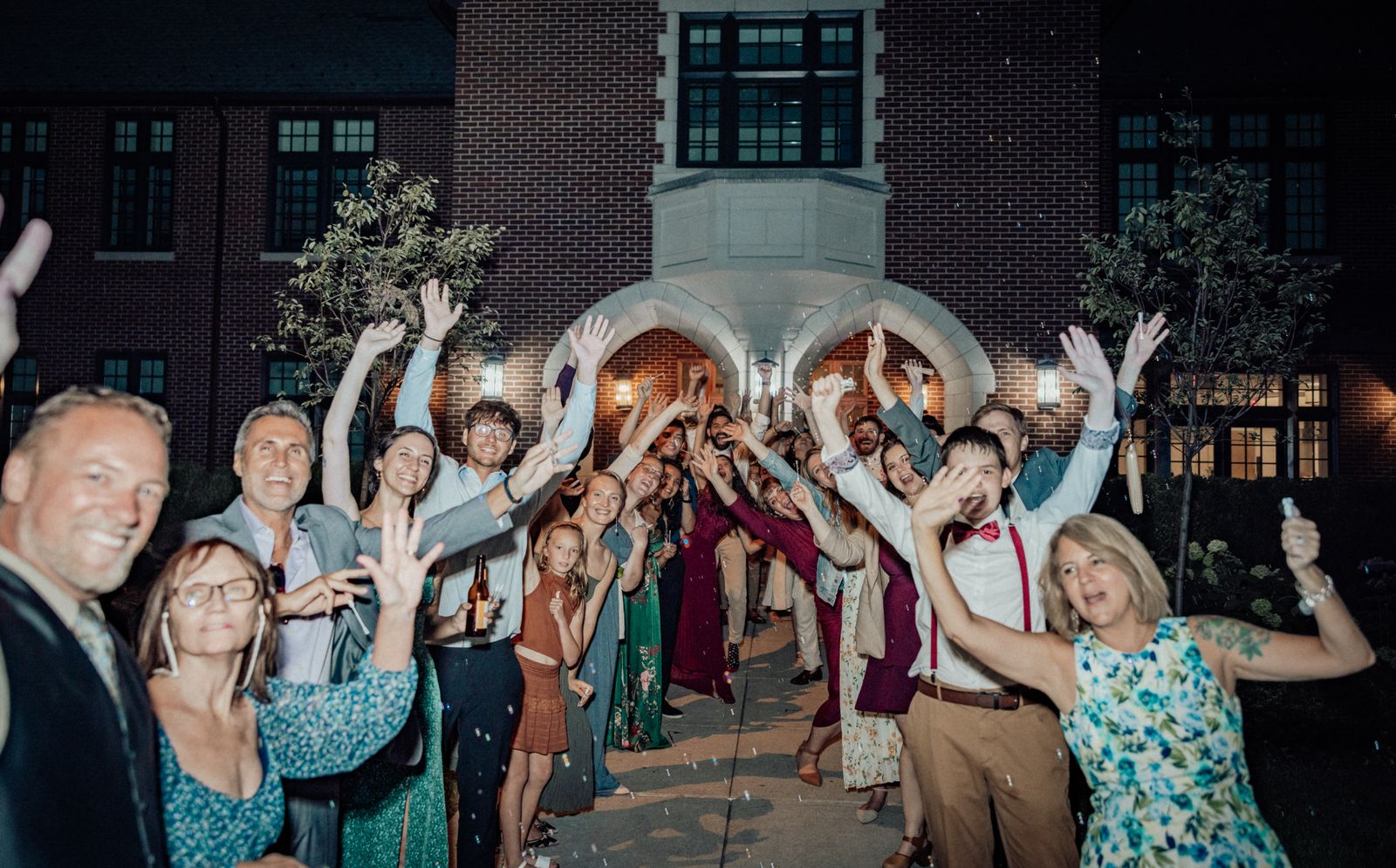 Guests cheering with raised arms outside the venue at night